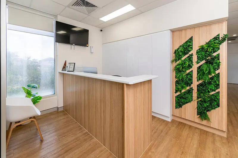 The clinic reception with a timber desk and living wall